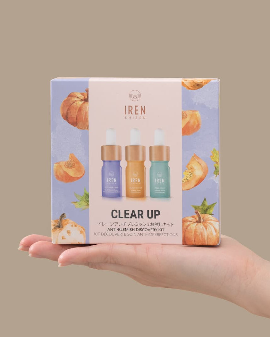 A hand holding a CLEAR UP Anti-Blemish Discovery Kit with pumpkins on it, perfect for improving complexion with the power of superfruits. Brand: IREN Shizen