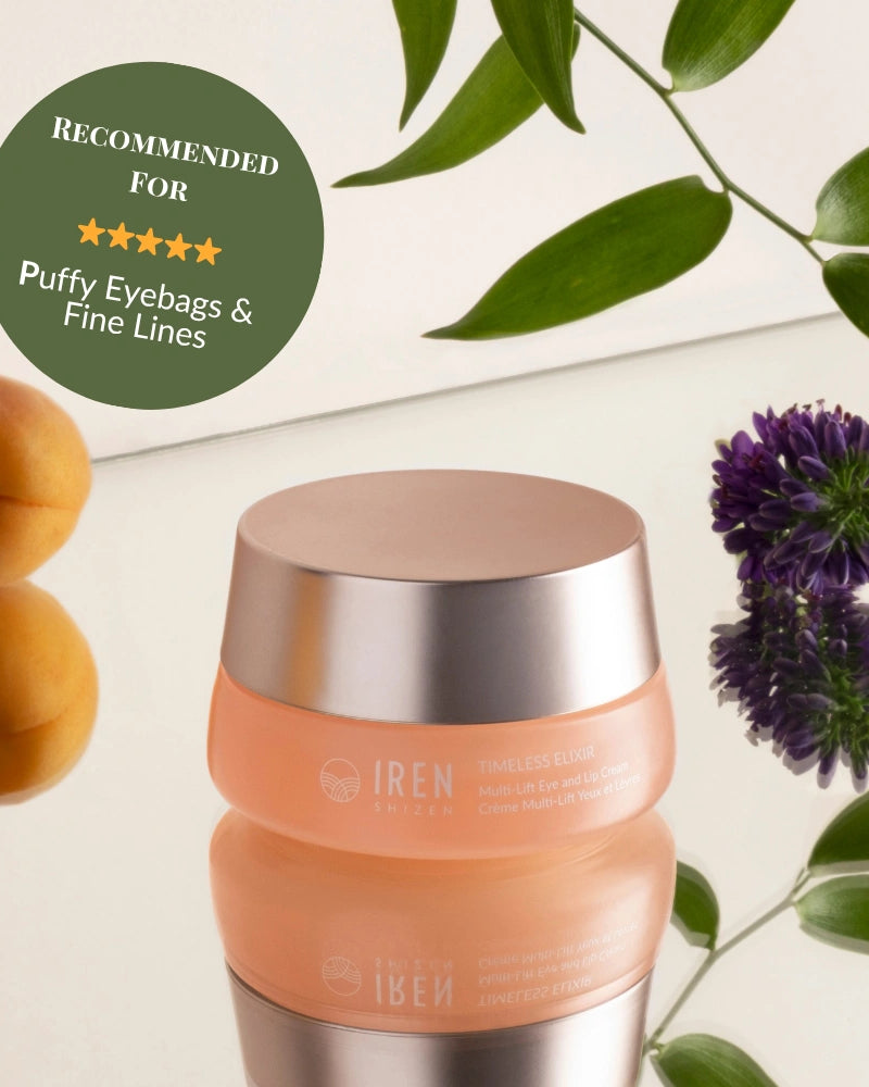 A jar of IREN Shizen TIMELESS ELIXIR Multi-Lift Eye and Lip Cream sits on a white surface with green leaves, a purple flower, and two apricots. A badge recommends this anti-aging cream for puffy eyebags and fine lines.
#show-lang-en #all-groups