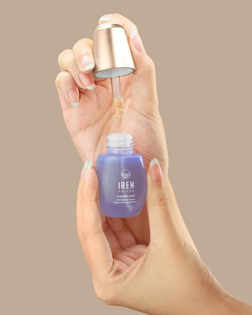 A hand holding a bottle of customised CLEARER DAYS Anti-Blemish Serum by IREN Shizen, a Japanese skincare brand inspired by onsen skincare, containing a blue liquid. #all-groups