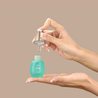 A hand dispenses KEEP CALM Soothing Serum by IREN Shizen from a blue bottle onto the palm, ideal for sensitive skin, with a plain beige background.