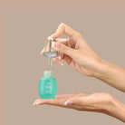 A person dispenses KEEP CALM Soothing Serum by IREN Shizen from a dropper bottle onto their palm against a plain beige background. #all-groups