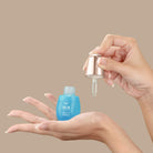 A woman's hand holding a bottle of custom Japanese skincare, the QUENCH-UP Hydrating Serum by IREN Shizen. #all-groups