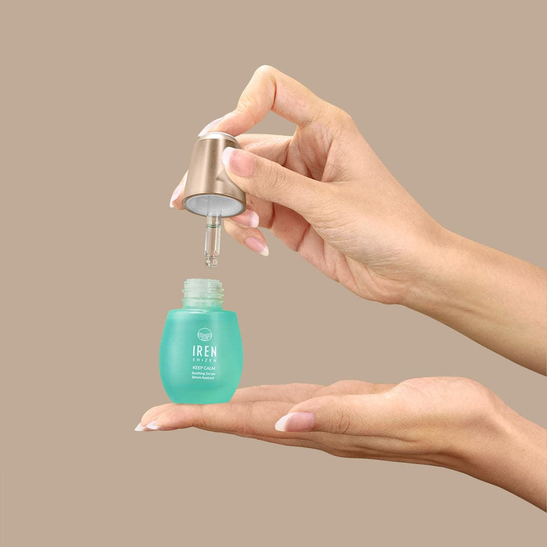 A woman's hand holding a bottle of customised KEEP CALM Soothing Serum by IREN Shizen, inspired by Japanese and onsen skincare. #all-groups